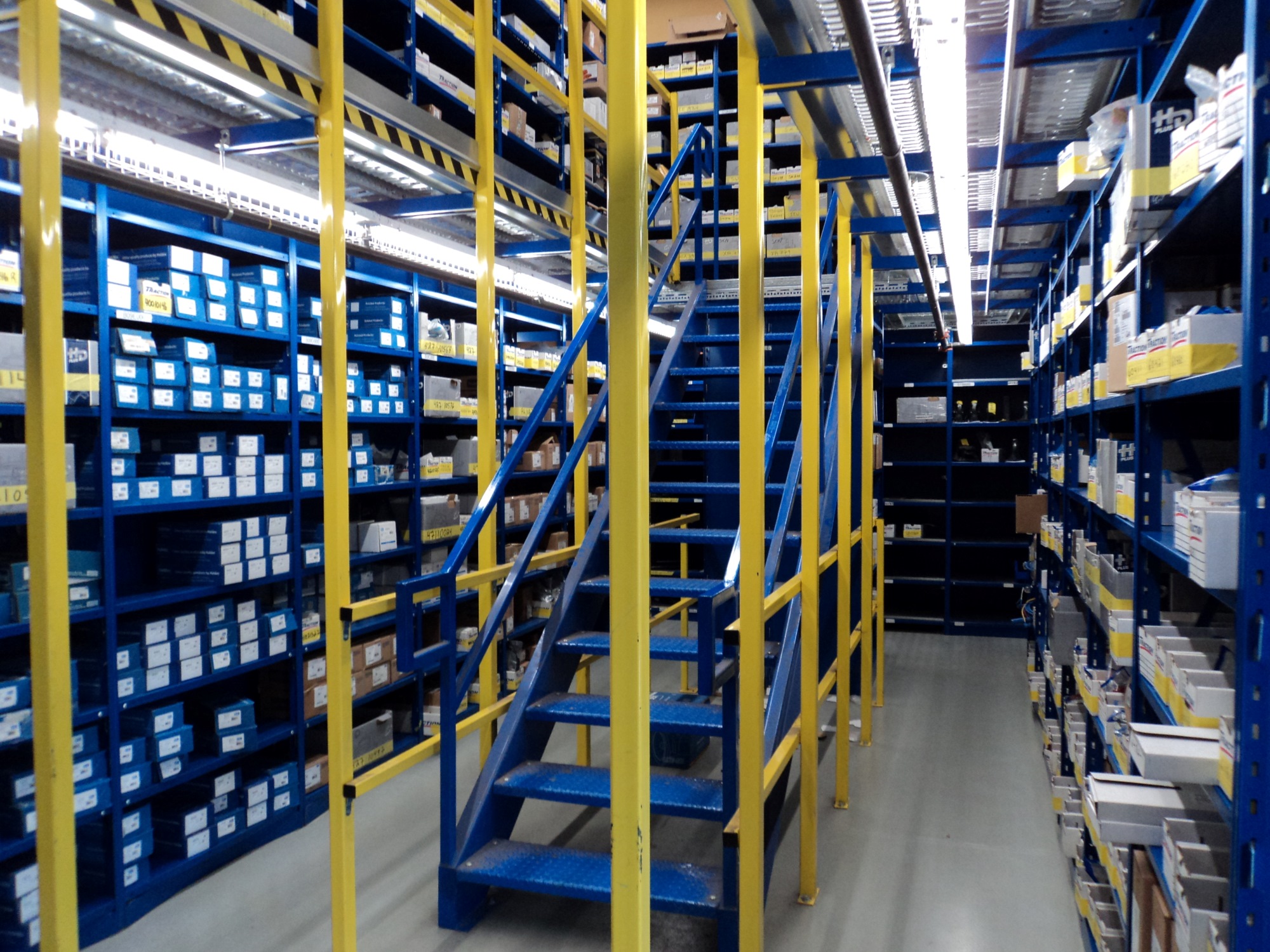 Entrepôt de pièce présenter à l'aide d'étagère métallique et d'une mezzanine.