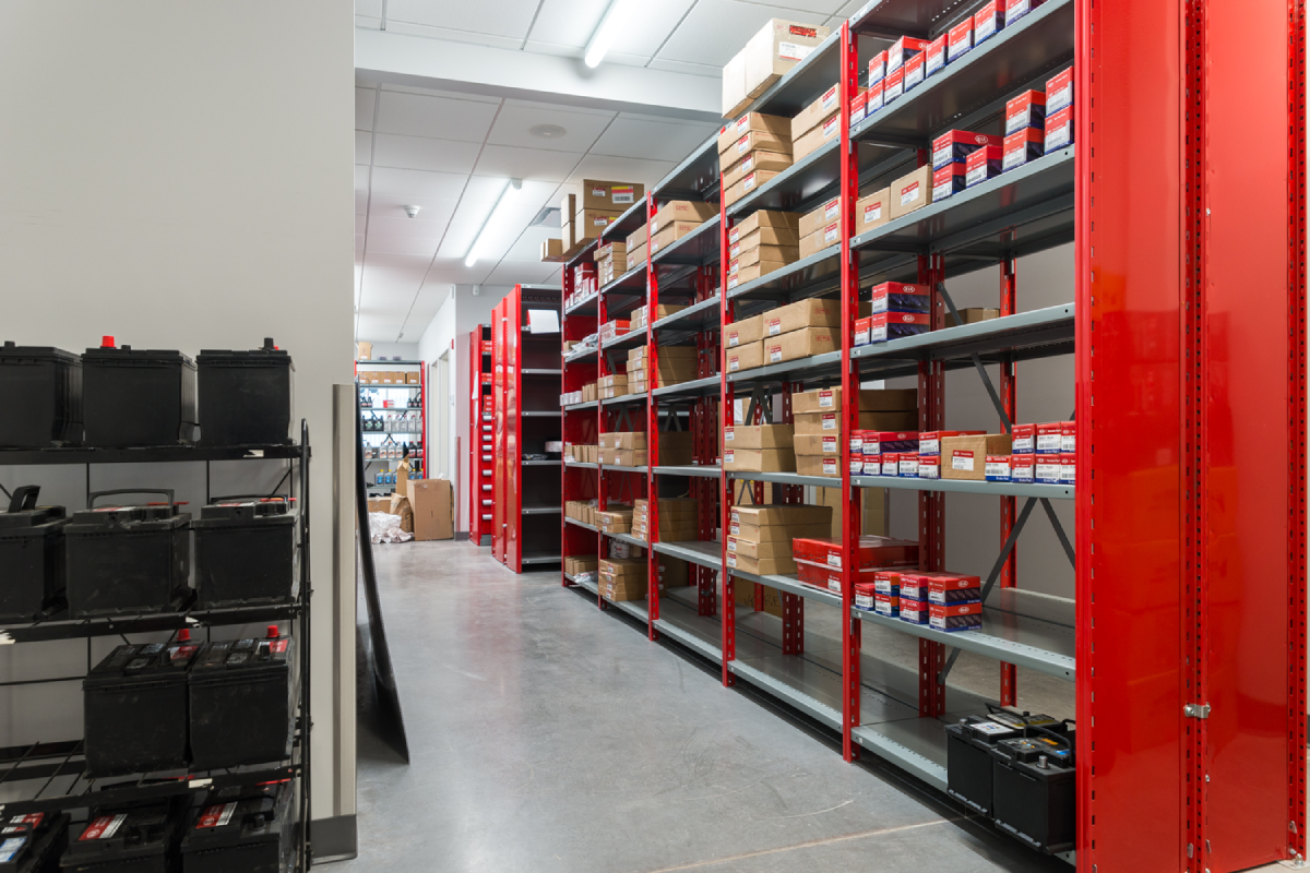 Grey and red industrial shelving in a KIA dealership.